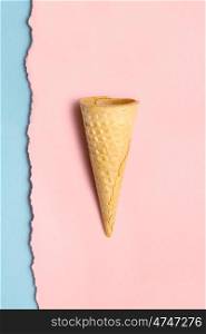 Creative still life of a sweet empty wafer cone on torn wall papers background.