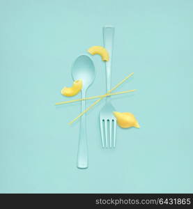 Creative still life of fork and spoon at a lunchtime with raw pasta served.