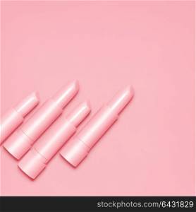 Creative still life of pink open lipsticks for makeup on pink background.