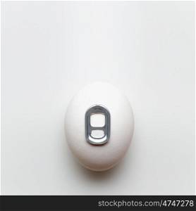 Creative still life photo of an egg with a can key on white background.
