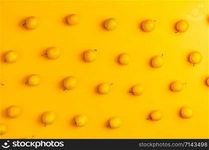 Creative summer pattern made of fresh yellow cherry plums on pastel yellow background. Fruit minimal concept. Flat lay.