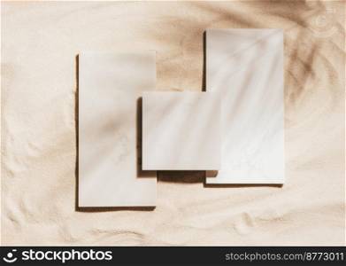Creative summer podium of marble tiles on the background of sand. Top view, copy space, bright sunlight and shadows. Showcase template for trendy natural cosmetics product with place for text, mockup. Creative summer podium of marble tiles background of sand, copy space, sunlight and shadows, mockup