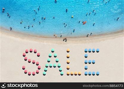 Creative text made from umbrellas on sandy beach and blue sea at sunny day. Aerial view of sea coast and text. Summer sale and discount. Background. Top view from drone of clear water, swimming people