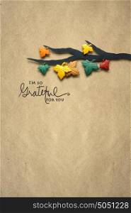 Creative thanksgiving day concept photo of a branch with leaves made of paper on brown background.