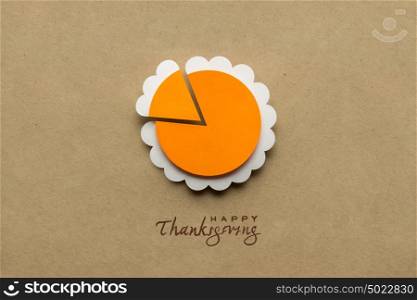 Creative thanksgiving day concept photo of a pumpkin pie made of paper on brown background.