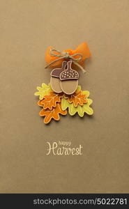 Creative thanksgiving day concept photo of acorns with leaves made of paper on brown background.