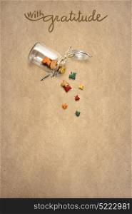 Creative thanksgiving day concept photo of leaves falling from the bottle on brown background.