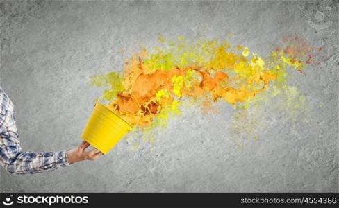 Creative thinking. Close up of hand splashing colorful paint from bucket