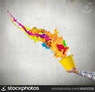 Creative thinking. Close up of hand splashing colorful paint from bucket