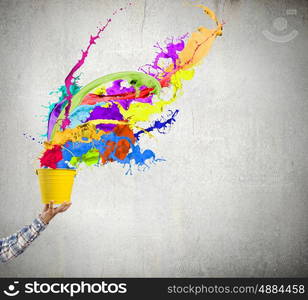 Creative thinking. Close up of hand splashing colorful paint from bucket