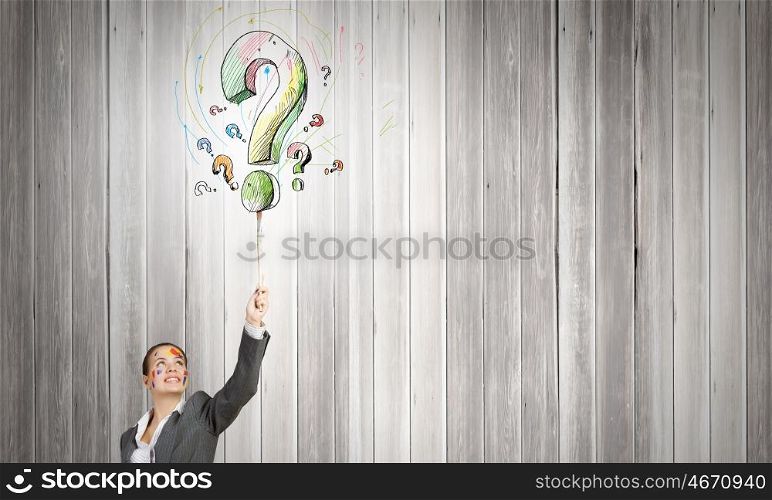 Creative thinking. Young attractive businesswoman painting question mark with paint brush