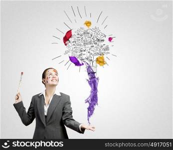 Creative thinking. Young attractive businesswoman with paint brush and colorful business sketches
