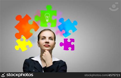 Creative thinking. Young attractive woman and colorful puzzles above her head