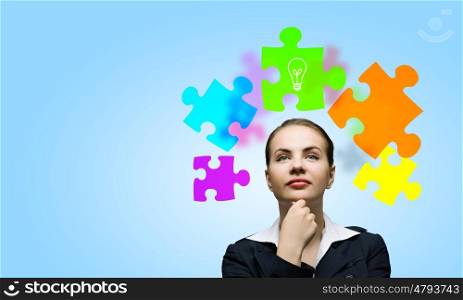Creative thinking. Young attractive woman and colorful puzzles above her head