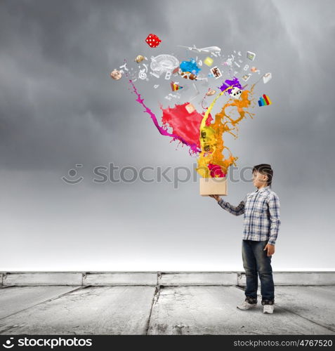 Creative thinking. Young boy splashing colorful paint from bucket