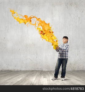 Creative thinking. Young boy splashing colorful paint from bucket