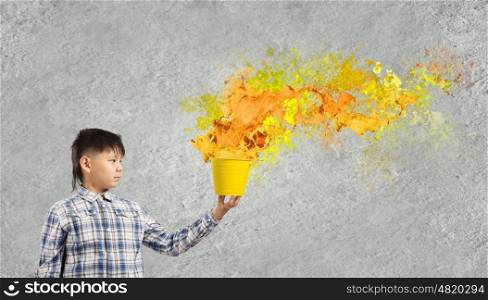 Creative thinking. Young boy splashing colorful paint from bucket