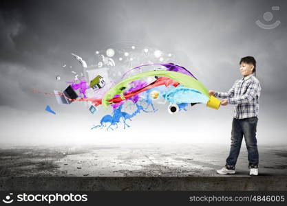 Creative thinking. Young boy splashing colorful paint from bucket