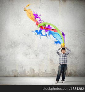 Creative thinking. Young boy splashing colorful paint from bucket