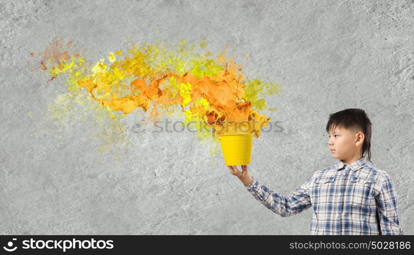 Creative thinking. Young boy splashing colorful paint from bucket