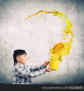 Creative thinking. Young boy splashing colorful paint from bucket