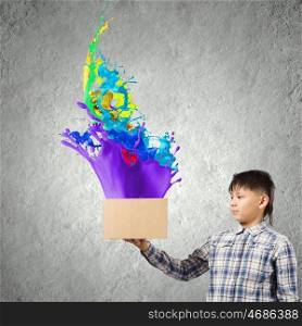 Creative thinking. Young boy splashing colorful paint from carton box