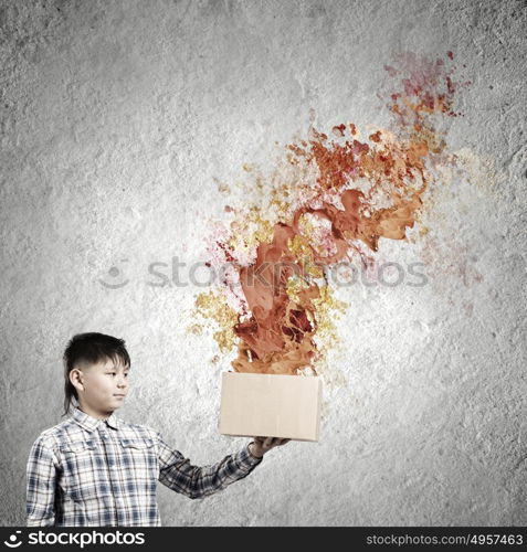 Creative thinking. Young boy splashing colorful paint from carton box