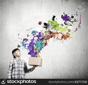 Creative thinking. Young boy splashing colorful paint from carton box