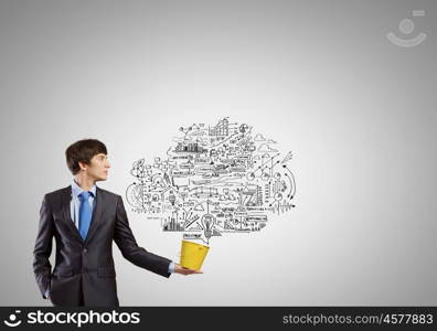 Creative thinking. Young businessman holding in hands yellow bucket