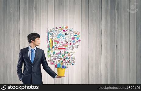 Creative thinking. Young businessman holding in hands yellow bucket