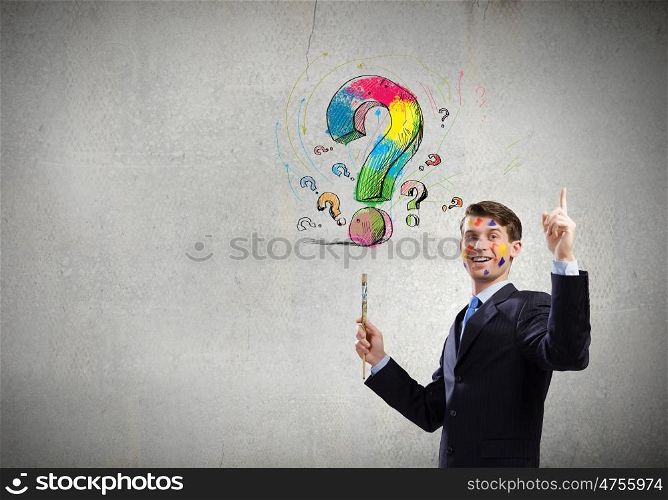 Creative thinking. Young cheerful businessman with paint brush in hand