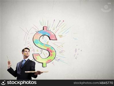 Creative thinking. Young handsome businessman drawing dollar sign with brush