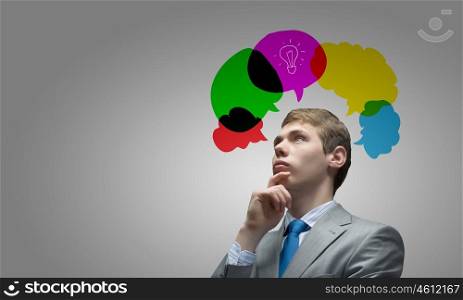 Creative thinking. Young thoughtful businessman and colorful speech bubbles above