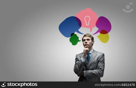 Creative thinking. Young thoughtful businessman and colorful speech bubbles above