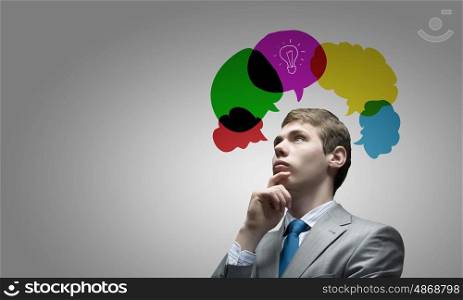 Creative thinking. Young thoughtful businessman and colorful speech bubbles above