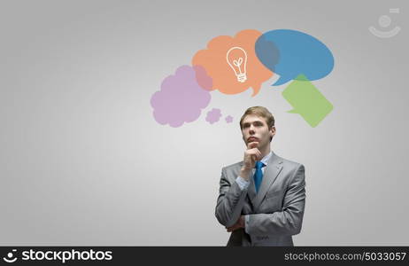 Creative thinking. Young thoughtful businessman and colorful speech bubbles above