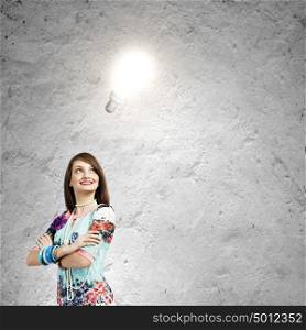 Creative thinking. Young woman in colorful dress looking at light bulb