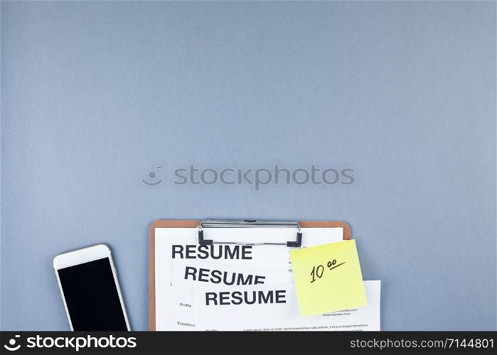 Creative top view flat lay of desk with resume documents and smartphone with copy space on blue background in minimal style. Concept of new job, hiring recruitment process, new team members screening