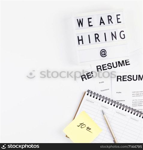 Creative top view flat lay of desk with we are hiring text on lightbox with copy space on white background in minimal style. Concept of new job, hiring recruitment process, new team members screening