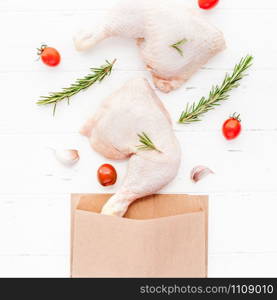 Creative Top view flat lay of fresh raw chicken legs with rosemary herbs garlic tomatoes on white wooden background with copy space. Food preparation recipe cooking concept