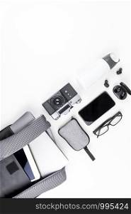 Creative top view flat lay of open backpack with laptop and tablet inside, mobile phone, copy space white background minimal style. Concept of modern man accessories for education, business and life