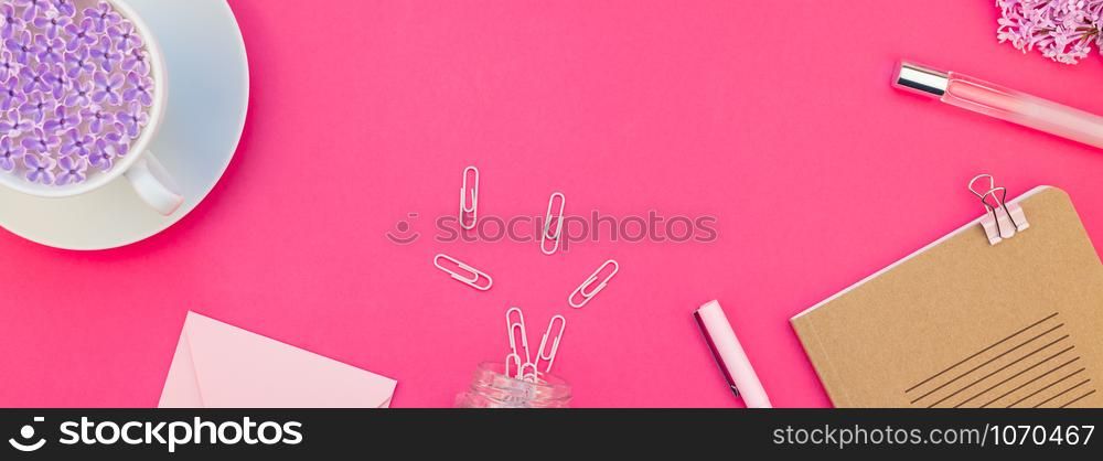 Creative top view flat lay of workspace desk styled design office supplies and cup of tea with copy space on a bright pink color paper long wide banner. Template for feminine blog social media
