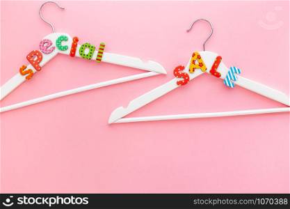 Creative top view flat lay white hangers special sale text pastel pink background copy space minimalism style. Template fashion feminine blog social media sale store promo design shopping concept
