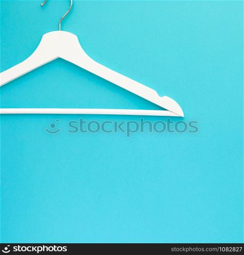 Creative top view flat lay white wooden hangers isolated bold blue turquoise background with copy space minimalism style. Template fashion feminine blog sale store promo design shopping concept