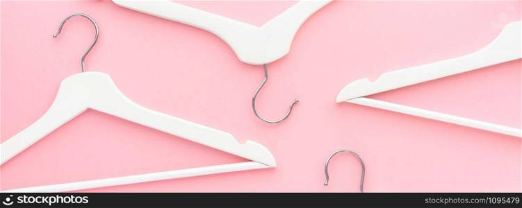 Creative top view flat lay white wooden hangers pastel millennial pink background with copy space minimalism style. Template fashion feminine blog social media sale store promo design shopping concept