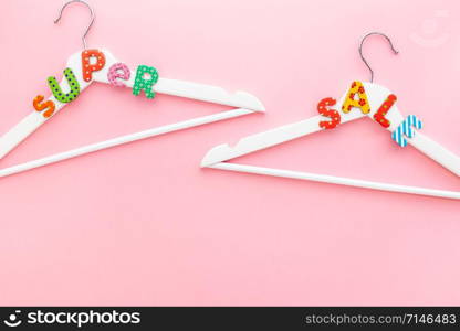 Creative top view flat lay white wooden hangers super sale text pastel pink background copy space minimalism style. Template fashion feminine blog social media sale store promo design shopping concept