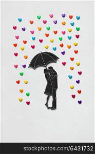 Creative valentines concept photo of a couple with umbrella and rain hearts on white background.