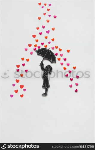 Creative valentines concept photo of a girl with umbrella and rain hearts on white background.