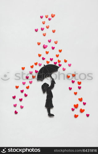 Creative valentines concept photo of a girl with umbrella and rain hearts on white background.