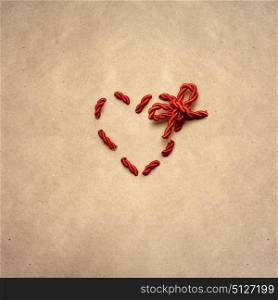 Creative valentines concept photo of a heart made of rope on brown background.